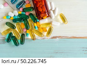 Top view assorted pharmaceutical medicine pills, tablets and capsules spilling on vintage wooden table for medicine background. Стоковое фото, агентство Ingram Publishing / Фотобанк Лори