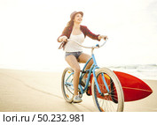 Surfer young woman riding her bicycle on the beach. Стоковое фото, агентство Ingram Publishing / Фотобанк Лори