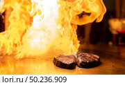Cooking of beef teppanyaki recipe japanese grilled beef on cooking pan using scraper with flame in background. Стоковое фото, агентство Ingram Publishing / Фотобанк Лори