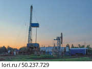 Drilling a well in an oil field. In the foreground is a mobile drilling rig. In the background, oil production at the field using a rocking machine. Summer. Beautiful sky and nature. Стоковое фото, фотограф Владимир Ендовицкий / Фотобанк Лори