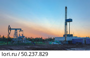Drilling a well in an oil field. In the foreground is a mobile drilling rig. In the background, oil production at the field using a rocking machine. Summer. Beautiful sky and nature. Стоковое фото, фотограф Владимир Ендовицкий / Фотобанк Лори