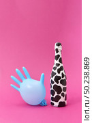 Wine bottle painted white and black spots with blue balloon rubber glove on a hot pink background, copy space.. Balloon rubber glove with painted white bottle with black spots. Стоковое фото, агентство Ingram Publishing / Фотобанк Лори