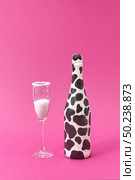 Holiday glass of white powder as a sugar and creative painted bottle with black spots on a hot pink background, copy space. Congratulation card.. Painted black spots wine bottle with glass of white powder. Стоковое фото, агентство Ingram Publishing / Фотобанк Лори