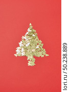 Creative Christmas decoration Tree from small shiny spruces on a red background with copy space. Greeting holiday card.. New Year Tree handmade from small sparkly fir. Стоковое фото, агентство Ingram Publishing / Фотобанк Лори