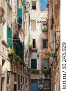 Narrow street in old town in Venice, Italy. Old buildings of mediveval times with ancient architecture.. Venetian buildings in Italy. Стоковое фото, агентство Ingram Publishing / Фотобанк Лори