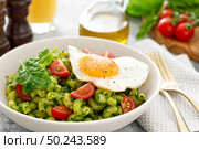Pasta cavatappi with spinach pesto, tomatoes and fried egg in bowl served for lunch. Стоковое фото, агентство Ingram Publishing / Фотобанк Лори