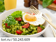 Pasta cavatappi with spinach pesto, tomatoes and fried egg in bowl served for lunch. Стоковое фото, агентство Ingram Publishing / Фотобанк Лори