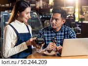 Asian customer using credit card with contactless nfs technology to pay a waitress for coffee purchase at table in cafe. Стоковое фото, агентство Ingram Publishing / Фотобанк Лори