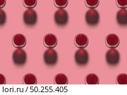 Rows with glasses of red wine alcohol drink on a pink background with hard shadows. Top view. Alcohol drink pattern.. Red wine glasses pattern with shadows. Top view. Стоковое фото, агентство Ingram Publishing / Фотобанк Лори