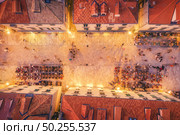 Aerial view of houses with red roofs at night in Dubrovnik, Croatia. Top view of beautiful architecture in old city. City lights, historical centre, buildings, walking people in illuminated streets. Стоковое фото, агентство Ingram Publishing / Фотобанк Лори