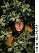 A woman concealing herself behind a bush, shutting her eyes. Стоковое AI-изображение, AI-художник Данила Большаков / Фотобанк Лори