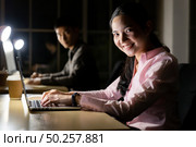 Young adult asian businessman and woman working late at night in their office with desktop computer and laptop. Using as hard working and working late concept. Стоковое фото, агентство Ingram Publishing / Фотобанк Лори
