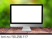 Blank white mock up computer monitor on a wooden table against blurred green natural background with bokeh, copy space. Working outside office concept.. Mockup computer screen on wooden table against a blurred background. Стоковое фото, агентство Ingram Publishing / Фотобанк Лори