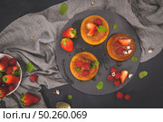 Caramel custard puddings on round slate on and dark kitchen countertop. Стоковое фото, агентство Ingram Publishing / Фотобанк Лори