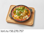 Homemade shakshouka dish cooked from fresh fried eggs with tomatoes, pepper, vegetables and herbs in a pan on a wooden board on a light grey background, copy space. Middle eastern traditional dish.. Pan with homemade traditional Shakshuka dish with spicy sauce from tomatoes. Стоковое фото, агентство Ingram Publishing / Фотобанк Лори