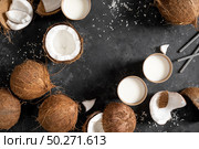 Coconut milk, whole and cracked coconuts on black background, top view. Стоковое фото, агентство Ingram Publishing / Фотобанк Лори