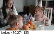 Children Drinking Juice on a Birthday Party at Home. Siblings, girls and a boy together celebrating a party, eating cake sitting at festive table. Little Kid Celebration. Surprise. Low key. Стоковое видео, видеограф Марина Демидюк / Фотобанк Лори