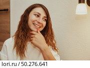 Reflecting on Aspirations a Woman Grins in a Bright Indoor Setting. Стоковое фото, фотограф Aleksandr Golubev / Фотобанк Лори