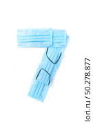 Figure 7, seven handmade from medical antibacterial protective blue face masks on a white background, copy space. Creative typeface for making up new numerical information.. Number seven made from protective medical masks on a white background. Стоковое фото, агентство Ingram Publishing / Фотобанк Лори