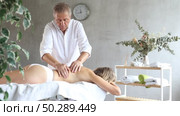 Skilled old masseur conducting back massage therapy for woman client in procedure room. Стоковое видео, видеограф Яков Филимонов / Фотобанк Лори