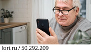 Hoary old man looking at web camera, holding phone, talking with children, wife online. Senior grandpa smiling chatting with friends, family via video call. Modern technologies and older generation. Стоковое фото, фотограф Марина Демидюк / Фотобанк Лори