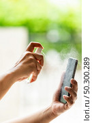 close-up cleaning mobile phone using alocohol spray from bottle spraying, disinfection for safety prevent and protect from infection of virus and germ Covid-19 coronavirus world pandemic. Стоковое фото, агентство Ingram Publishing / Фотобанк Лори