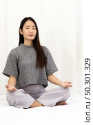Asian Woman do meditate to relax and reduce stress and strain for good mental health cause from city lockdown from coronavirus COVID-19 Pandemic. Meditation relax and leisure activity concept. Стоковое фото, агентство Ingram Publishing / Фотобанк Лори