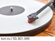 Vintage old-fashioned turnable record player with retro vinil disc on a wooden table, copy space. Close up view. Popular disco trends 60s, 70s, 80s, 90s.. Old-fashioned turnable record player on a wooden background. Стоковое фото, агентство Ingram Publishing / Фотобанк Лори