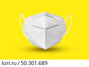 Medical antibacterial protective face mask floating above yellow background with soft shadows, copy space. Concept of prevention from respiratory sickness and viruses.. Floating medical mask above yellow background with soft shadows. Стоковое фото, агентство Ingram Publishing / Фотобанк Лори