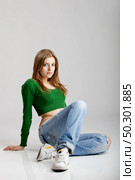 Beautiful young fashion model seated on the floor. Стоковое фото, агентство Ingram Publishing / Фотобанк Лори