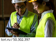 Asian warehouse manager discuss with warehouse worker using digital tablet to assign job inside distribution warehouse. Reopening business warehouse technology and logistic concept. Стоковое фото, агентство Ingram Publishing / Фотобанк Лори