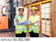 Portrait of Asian warehouse manager and worker arm crossed with warehouse worker operate forklift to check inventory in background. Reopening business warehouse technology and logistic concept. Стоковое фото, агентство Ingram Publishing / Фотобанк Лори