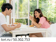 Asian young couple eating out together at new normal social distance restaurant. Woman take photo as food blogger influencer or vlogger through table shield partition. Restaurant new normal lifestyle. Стоковое фото, агентство Ingram Publishing / Фотобанк Лори