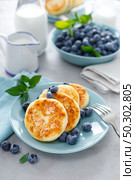 Cottage cheese pancakes, sweet curd fritters with berries, syrniki with honey and fresh blueberry on breakfast table. Стоковое фото, агентство Ingram Publishing / Фотобанк Лори