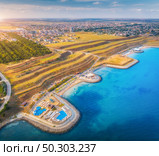 Aerial view of beautiful sandy beach, blue sea, restaurants on the promenade, pool, umbrellas, swimming people in clear water, green trees at sunset in summer. Top view of seafront, yellow hills, city. Стоковое фото, агентство Ingram Publishing / Фотобанк Лори