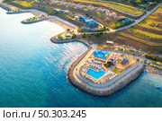 Aerial view of beautiful sandy beach, blue sea, restaurants on the promenade, pool, umbrellas, clear water, cottage town, green trees at sunset in summer. Top view of seafront. Tropical landscape. Стоковое фото, агентство Ingram Publishing / Фотобанк Лори
