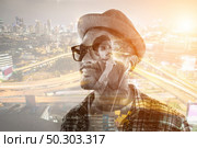Young hipster man in earphones holding smartphone isolated on the white background. Стоковое фото, агентство Ingram Publishing / Фотобанк Лори