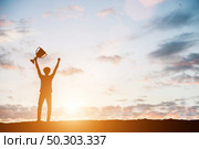 Silhouettes of man won a trophy, achieved with his work. Стоковое фото, агентство Ingram Publishing / Фотобанк Лори