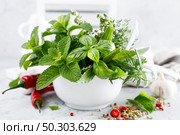 Bunch of aromatic herbs in mortar on kitchen table. Стоковое фото, агентство Ingram Publishing / Фотобанк Лори