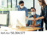 Three asian business person discuss their work in morning after office reopen due to coronavirus COVID-19 pandemic. They wear protective face mask to prevent infection. New normal office life concept. Стоковое фото, агентство Ingram Publishing / Фотобанк Лори