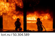 Firefighters using water fog fire extinguisher to fighting with the fire flame in large building. Firefighter and industrial safety disaster and public service concept. Стоковое фото, агентство Ingram Publishing / Фотобанк Лори
