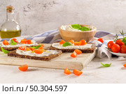 Rye bread bruschetta with cream cheese, olive oil and basil dip, cherry tomatoes, fresh basil leaves on wooden board. Стоковое фото, агентство Ingram Publishing / Фотобанк Лори