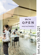 Reopening restaurant signage with social distance for new normal restaurant with background of asian waiter and waitress prepare restaurant before open. New normal restaurant lifestyle concept. Стоковое фото, агентство Ingram Publishing / Фотобанк Лори