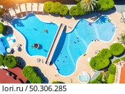 Aerial view of pool, swimming people in transparent blue water, umbrellas, sunbeds, green trees at sunset. Summer holidays. Top view of pool, deck chairs. Relax and leisure in luxury resort in Europe. Стоковое фото, агентство Ingram Publishing / Фотобанк Лори