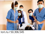 Seriously injured patient with oxygen mask on gurney stretcher bed pushed by medical team of doctor nurse and paramedic to the Operating Room. Emergency health care and medical hospital concept. Стоковое фото, агентство Ingram Publishing / Фотобанк Лори