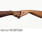 African man touching knuckles with dark-skinned woman as sign of agreement, partnership and cooperation. Two people holding hands in fist bump while greeting each other in informal modern handshake. Стоковое фото, агентство Ingram Publishing / Фотобанк Лори