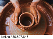 Dirty hands of potter on rotating clay jug. Unfinished jug. Стоковое фото, агентство Ingram Publishing / Фотобанк Лори