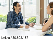 Asian young couple eating out together at new normal social distance restaurant with table shield partition reduce infection of coronavirus covid-19 pandemic. Restaurant new normal lifestyle. Стоковое фото, агентство Ingram Publishing / Фотобанк Лори