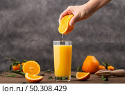 A glass of orange juice and a person squeezing an orange in it. Glass of orange juice and a person squeezing an orange in it. Стоковое фото, агентство Ingram Publishing / Фотобанк Лори