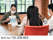 Group of asian and caucasian business person team meeting and brainstorm in meeting room after office reopen, they wear protective face mask as new normal practice to prevent coronavirus infection. Стоковое фото, агентство Ingram Publishing / Фотобанк Лори